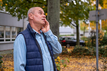 bald man hearing or listening deeply, ear with pained expression, discomfort loud noise,...