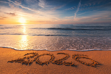 Happy New Year nature background concept, ocean sunrise and 2026 text on the beach sand and sea wave