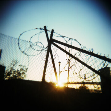 Sun setting behind barbed wire fence
