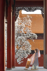 Woman in a flowing hanfu standing gracefully amidst blooming flowers.