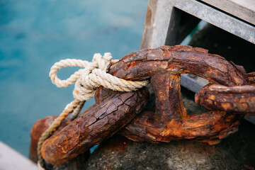 Rusty chain secured with rope by the water