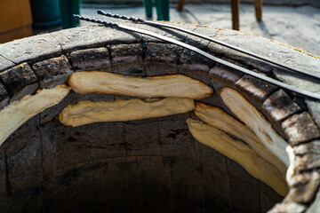 Closeup of a few raw pitas to make bread being baked in a tandoor