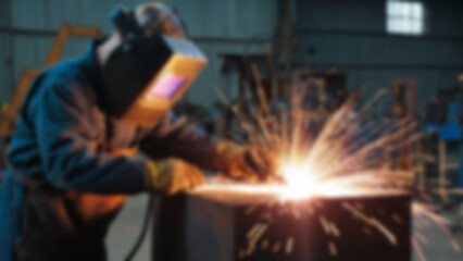 blurry image of someone welding iron, there are sparks, the person is wearing safety clothing, blurry wallpaper