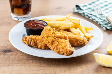 Crispy fried chicken tenders with french fries on wooden table