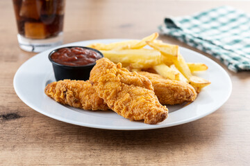 Crispy fried chicken tenders with french fries on wooden table