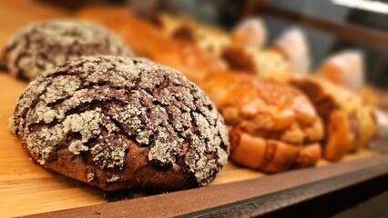 Various kinds of delicious breads, pastries and cookies displayed in a bakery shop's glass case. Tempting snack arrangement.
