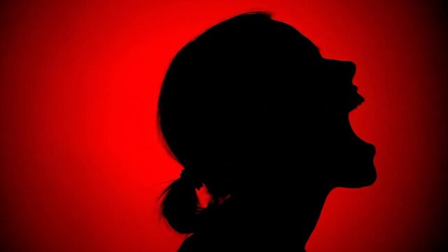Silhouette of a woman's head in profile, mouth open, against a red background