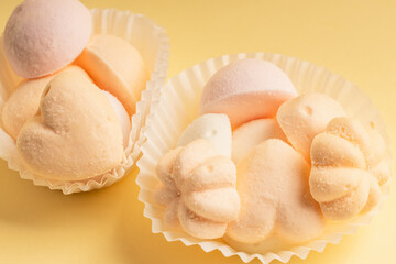 White paper tartlets with marshmallows on a delicate yellow background.