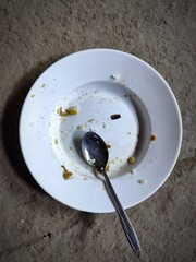  A dirty spoon and plate that are white because they have not been washed.