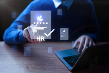 Human resources professional analyzing candidate profiles through a laptop at an office setting during the evening