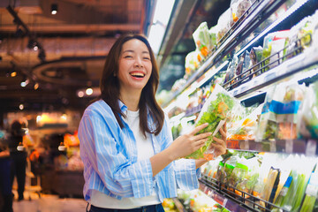 Asian woman shopping in supermarket, smiling and choosing healthy groceries ,Lifestyle concept of consumer behavior in modern retail market.