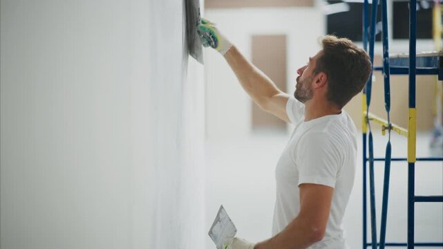A Skilled Craftsman Applying Finishing Touches to a Wall in a Renovated Space, Showcasing Precision and Attention to Detail in Interior Painting or Plastering Work