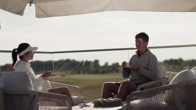 Happy woman and man talk drinking coffee after golf training