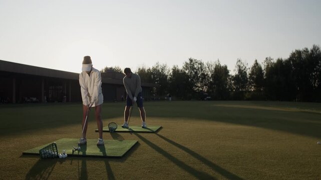 Friends train professional golf swings taking balls from baskets