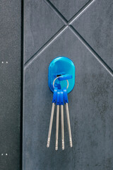 bright keys with blue decor dangle from sleek door lock on modern door, reflecting contemporary style in chic urban setting, ideal for any home entry or office space. close up.