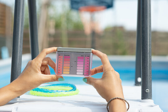 Woman Testing Backyard Swimming Pool Water Quality with a Handheld Tester