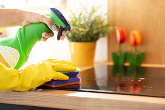 Person wearing yellow gloves cleaning induction cooktop