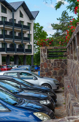 view of parking lot with cars and hotel decorated with flowers, concept of car travel and comfortable rest