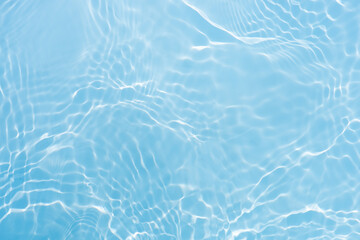 Blue water with ripples on the surface. Defocus blurred transparent blue colored clear calm water surface texture with splashes and bubbles. Water waves with shining pattern texture background.