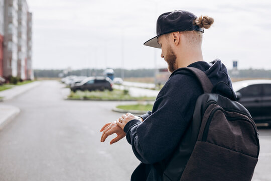 Young man in casual urban style checking smartwatch outdoors. - Powered by Adobe