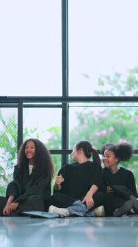 Girls of diverse ethnicities including Asian, White , African American&mdash;celebrate their graduation together in scool, wearing caps and gowns, smiling brightly as they share this proud and happy milesto