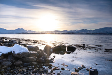 Snow covered Robukta coast of Norwegian fjord near Troms at Christmas time. A sunny winter day in Northern Norway above the Arctic Circle