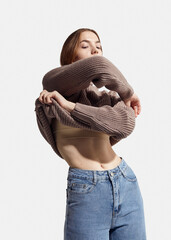 A beautiful woman takes off her beige autumn sweater