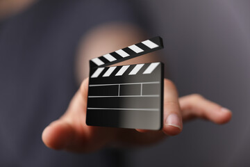 Close-up of a hand presenting a digital movie clapperboard. Perfect for film, video, and production concepts.