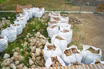 Bricks collected in bags and a pile of stones lying next to them after restoration. Architecture renovation concept: selective dismantling, salvage for reuse and heritage-friendly building methods