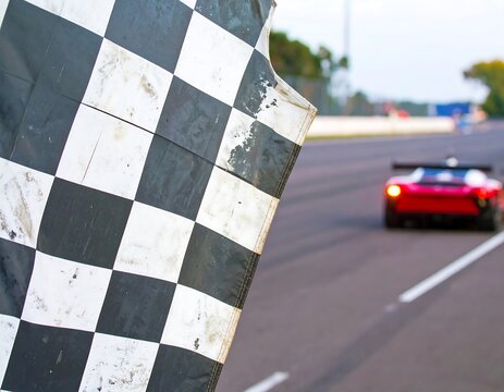 Checkered flag waving at race track. Blurred view of racing car