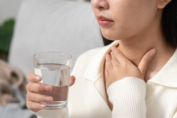 Asian woman put on neck due to a sore throat. female tonsillitis causes a inflammation. treated by taking water, taking antibiotics, consult a doctor, virus, corona virus, Influenza, flu