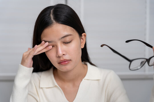 Eye problems, Asian women with tired and irritated eyes, eye rubbing, dry, eye pain after work, migraine, headache, blurred vision, photophobia, working in the dark, blue light from computer