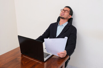 A businessman at his working desk showing stressed expression