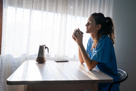 Nurse enjoying hot coffee during relaxing break at home - Powered by Adobe