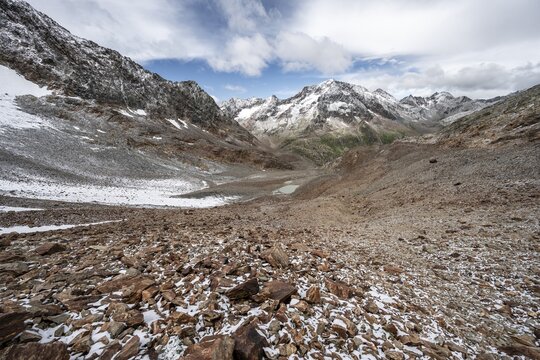 View of steep rocky mountain landscape with fresh snow in summer, descent from the Hornscharte, on the Wiener H&ouml;henweg, behind summit Roter Knopf, Schober group, Hohe Tauern National Park, Carinthia, Austria