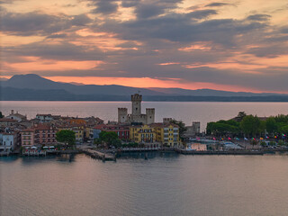 Obraz premium Picturesque aerial view of Sirmione, Lake Garda, Italy, at sunrise. Rocca Scaligera, historic town, medieval fortress, Italian architecture, and scenic panoramic view for travel and tourism.