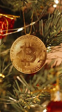 Vertical video. Close-Up of Bitcoin Ornament Hanging on Christmas Tree Among Ribbons Berries and Decorative Drums with Warm Lighting, Symbolizing Festive Crypto Investment