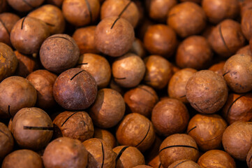 Texture of delicious macadamia nuts as background, close-up. Top view of delicious brown macadamia nuts with slits for opening and eating right away