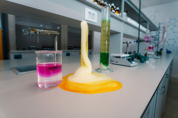 Colorful chemical reaction overflowing from a graduated cylinder and creating foam on a laboratory...