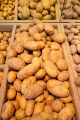 Lots of raw potatoes lying in a tray on the display case of a vegetable shop. Natural not perfect many potatoes. Close-up