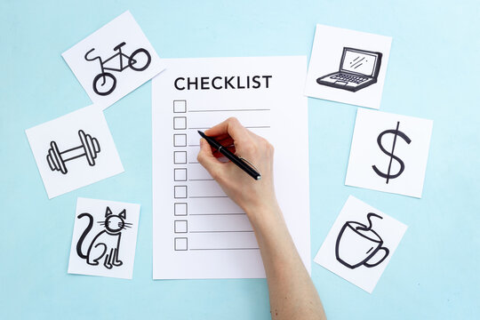 Hand writes in Checklist and many paper cards with hand drawing of different life activities, top view. Life balance and planning concept.