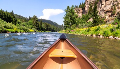 Fototapeta premium A serene river journey unfolds from within a wooden canoe, showcasing a tranquil waterway bordered by lush greenery and vibrant wildflowers.