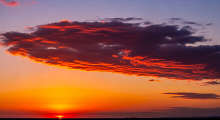 A vibrant sunset paints the sky with fiery hues, casting a warm glow over the horizon.