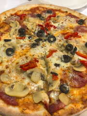 Savory pizza topped with mushrooms, olives, and peppers at a cozy restaurant