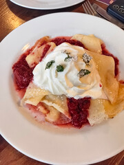 Delicious crepes topped with whipped cream and berry sauce during brunch delight