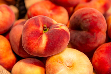 Flat peaches. Juicy ripe peaches. Background of red ripe peaches from figs, agricultural produce, sale at farmers market. Harvest season.