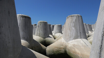 Closeup of huge concrete wave breakers piled up on a beach
