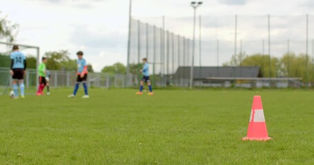 A group of enthusiastic youths is practicing soccer drills on a grassy field marked by cones. Dressed in blue jerseys, they focus on skill development to enhance their gameplay - Powered by Adobe