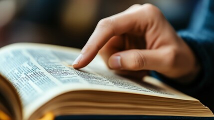 Naklejka premium Close-up of a hand gently tracing words on an open book page, symbolizing reading and exploration.