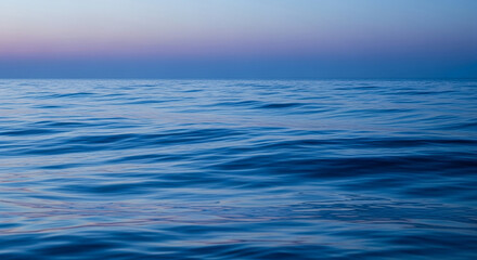Fototapeta premium Blue water surface texture, gentle waves, tranquil sea scene at sunset, evokes calmness and serenity, ideal for relaxation or travel themes